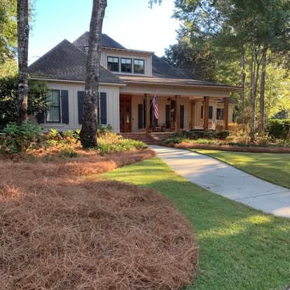White Fairhope farmhouse with American flag and thick fresh pine straw beds in the foreground